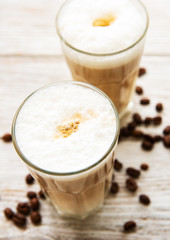 Two glasses of latte coffee and coffee beans