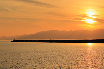 琵琶湖の夕景と突堤の先の釣り人のシルエット