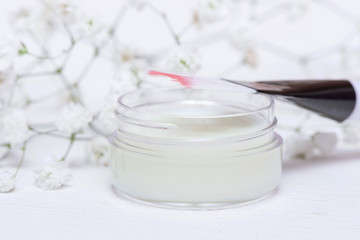 Cosmetic natural cream in a jar on a white table background.