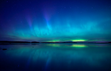 Fototapeta na wymiar Northern lights dancing over calm lake in Farnebofjarden national park in Sweden.