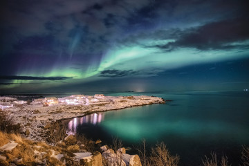 Fototapeta na wymiar Scandinavian village illumination with northern lights on snow cape