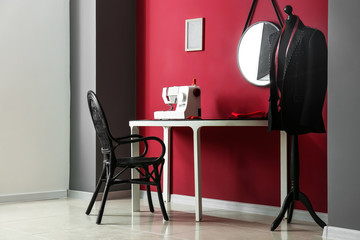 Stylish workplace of tailor with sewing machine in workshop