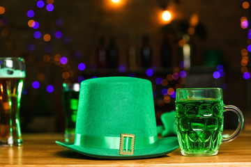 Mug of green beer and leprechaun hat on wooden table in pub. St. Patrick's Day celebration