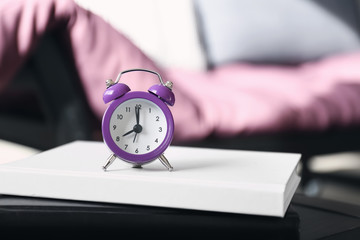 Alarm clock and books on table in room