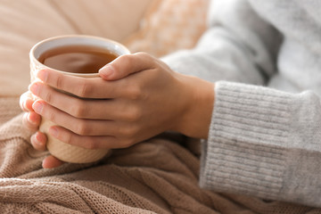 Young woman drinking hot tea at home, closeup