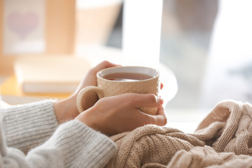 Young woman drinking hot tea at home, closeup