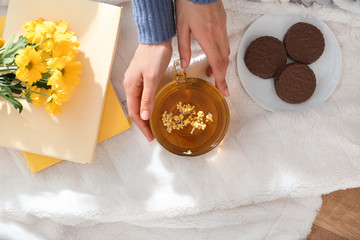 Young woman drinking hot tea and eating cookies at home