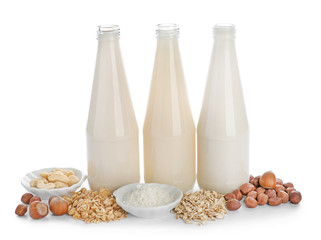 Bottles of different vegan milk on white background