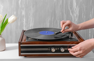 Woman switching on record player with vinyl disc