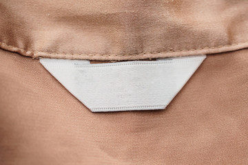 blank white clothing label on brown fabric texture background