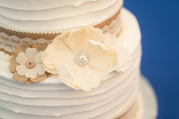 burlap ribbon and white paper flower on wedding cake
