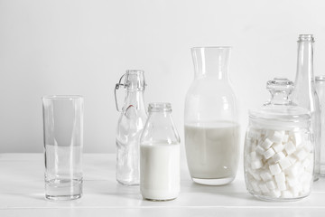 Glassware with milk and sugar on white table