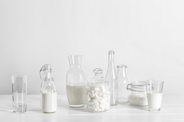 Glassware with milk and sugar on white table
