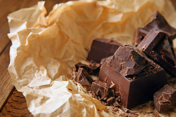Pieces of tasty dark chocolate on parchment