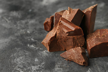 Pieces of tasty dark chocolate on grunge background