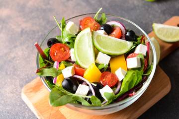 Healthy salad with feta cheese in bowl on table