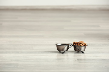 Fototapeta na wymiar Bowls with pet food on floor