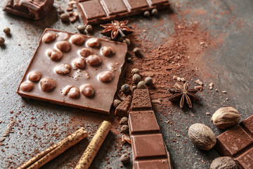 Sweet tasty chocolate, cinnamon and nuts on grey background