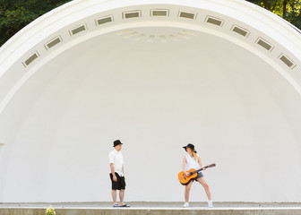 Woman playing guitar, man jumping next to her