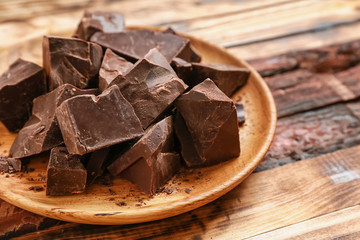 Plate with tasty chocolate on wooden background