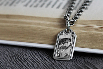 Money talisman on a chain and book, wooden background