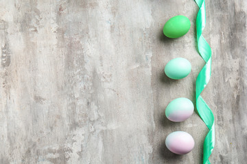 Beautiful Easter eggs and ribbon on grey background