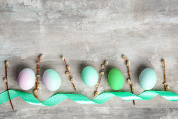 Beautiful Easter eggs, pussy willow branches and ribbon on grey background