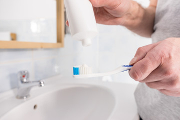 Person putting toothpaste on toothbrush