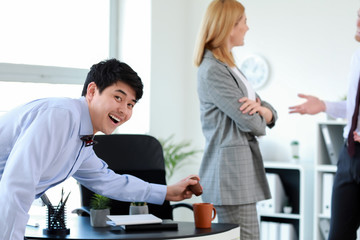 Asian man playing a prank on his colleague in office. April Fools' Day prank