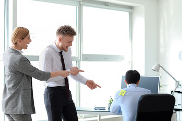 Friends playing a prank on their colleague in office. April Fools' Day prank