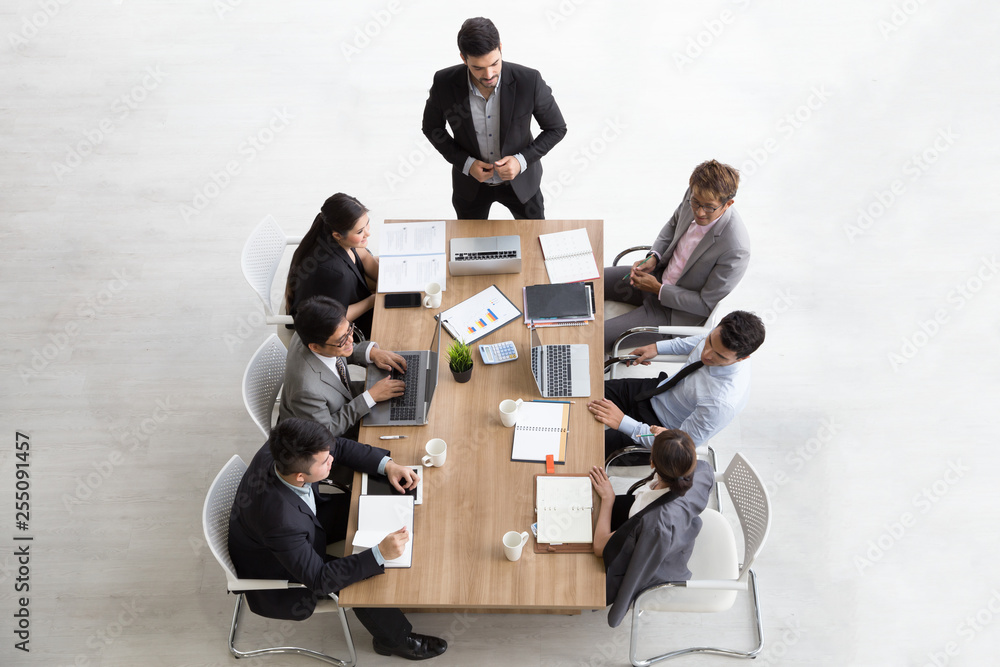 Wall mural Top view of group of multiethnic busy people working in an office, Aerial view with businessman and businesswoman sitting around a conference table with blank copy space, Business meeting concept