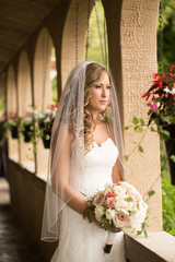 Beautiful young bride with veil poses in a European setting