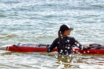Attractive young girl with sup board standing in sea