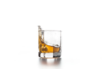 Whiskey splash in glass with ice on light background..