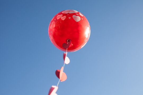 A little girl with red balloon on the blue sky.