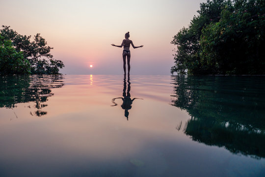 Beautiful woman practice yoga pose on the pool above the Mountain peak in the evening in front of beautiful nature views in india goa wildernest nature resorte .romance sunset in the mountains