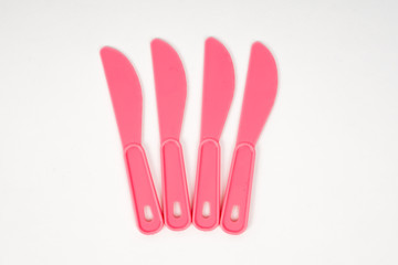 Pink plastic children knives on a white background