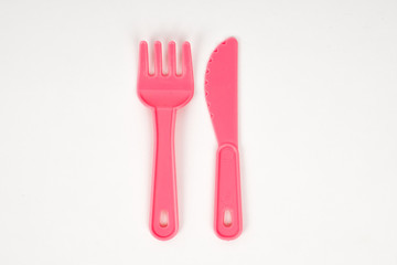 Pink plastic baby fork and knife on a white background