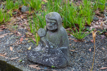 Fototapeta na wymiar Old statue of a seated Buddhist monk made of stone close-up