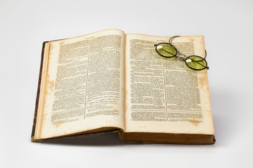 Obraz premium Old french dictionary lies open with old spectacles against a white background
