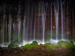 滝を夜間に撮影、筋状に幾つか流れ落ちて水紫吹きが白く輝いています、岩には緑色した苔が綺麗です。