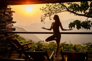 woman in tropical open yoga studio place a view outside to the hills while sunset.girl in eco hotel...
