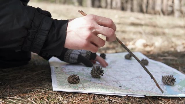 Traveler in the forest paves the route on the map