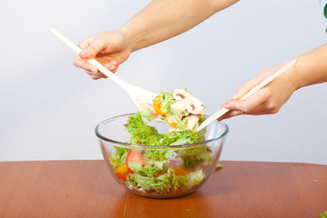 Women's hands are preparing a salad