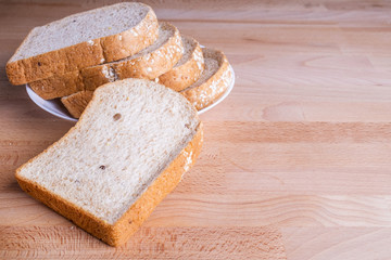 Slice whole wheat bread on wooden floor background.