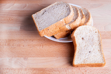 Slice whole wheat bread on wooden floor background.