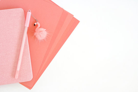 Pink sheets of paper, notepad and pen with flamingo on white background