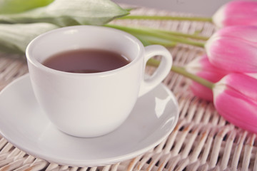 Fototapeta na wymiar A cup of tea and pink tulips on the table