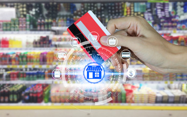Hand holding credit card and Supermarket store abstract blurred background with online shopping icons technology, Online shopping concept.