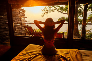 Young woman on f the house in the beautiful forest panoramic windows eco hotel in the jungle
